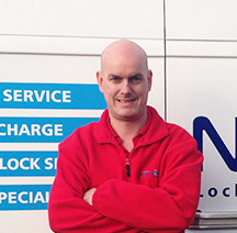 locksmith in red fleece jacket stood smiling in front of a work van